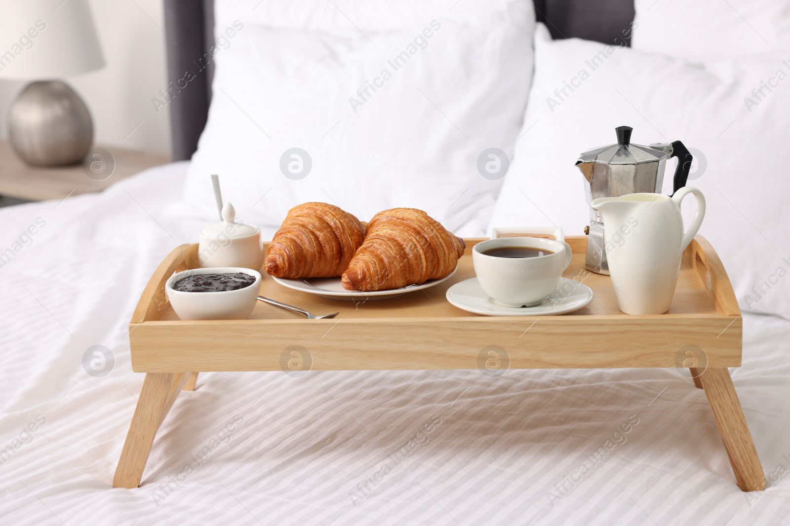 Wooden tray with tasty breakfast on bed at home Photo of Wooden tray with tasty breakfast on bed at home