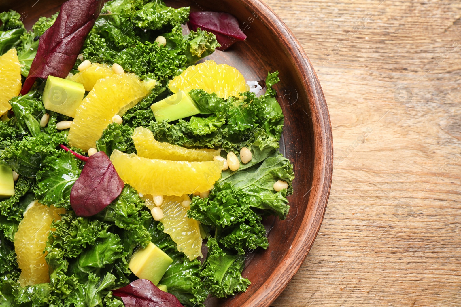 Photo of Tasty fresh kale salad on wooden table, closeup