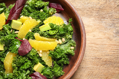 Tasty fresh kale salad on wooden table, closeup