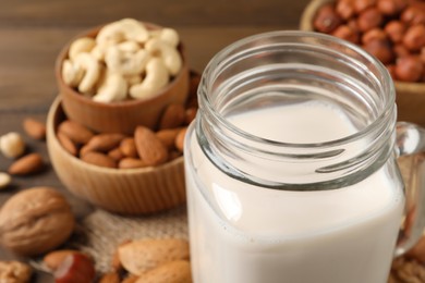 Photo of Vegan milk and different nuts on table, closeup