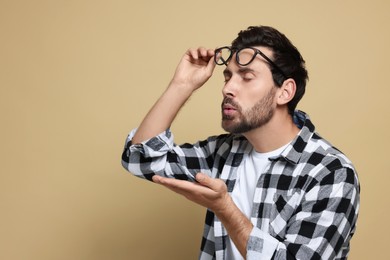 Handsome man blowing kiss on beige background. Space for text