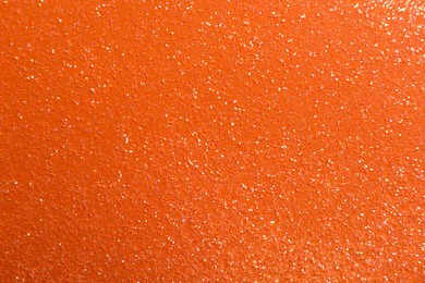 Shiny bright glitter on orange background, flat lay