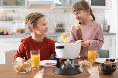 Happy kids enjoying fondue dinner at home