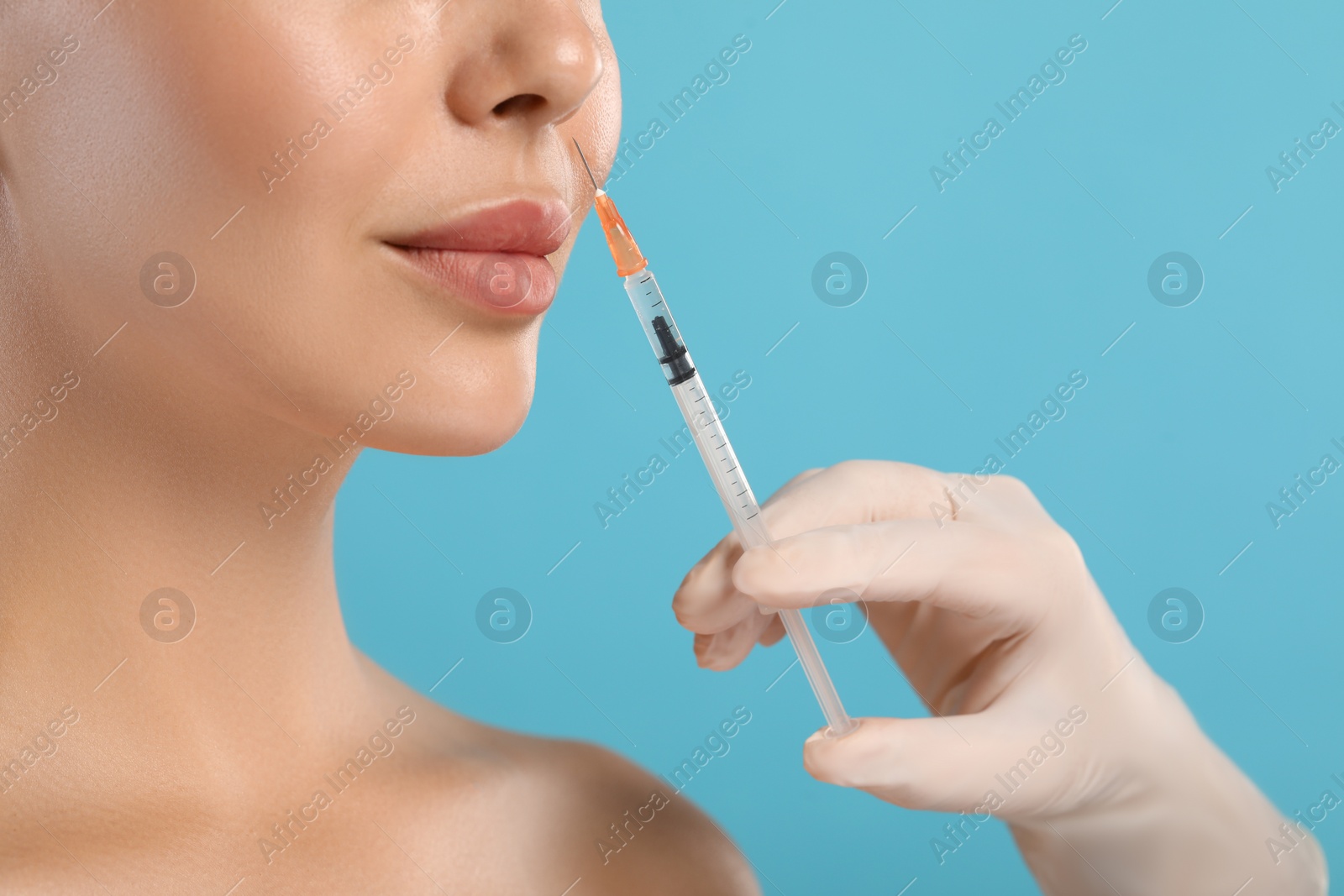 Photo of Doctor giving facial injection to young woman on light blue background, closeup. Cosmetic surgery