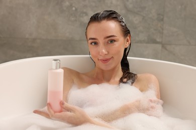 Photo of Woman taking bath with shower gel in bathroom