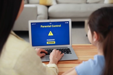 Photo of Mother installing parental control app on laptop to ensure her child's safety at home, closeup