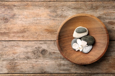 Photo of Plate with spa stones and space for text on wooden background, top view