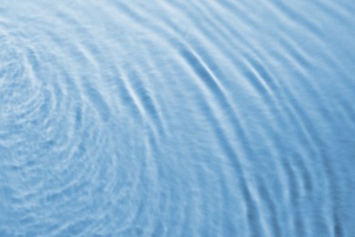 Image of Rippled surface of clear water on light blue background, closeup