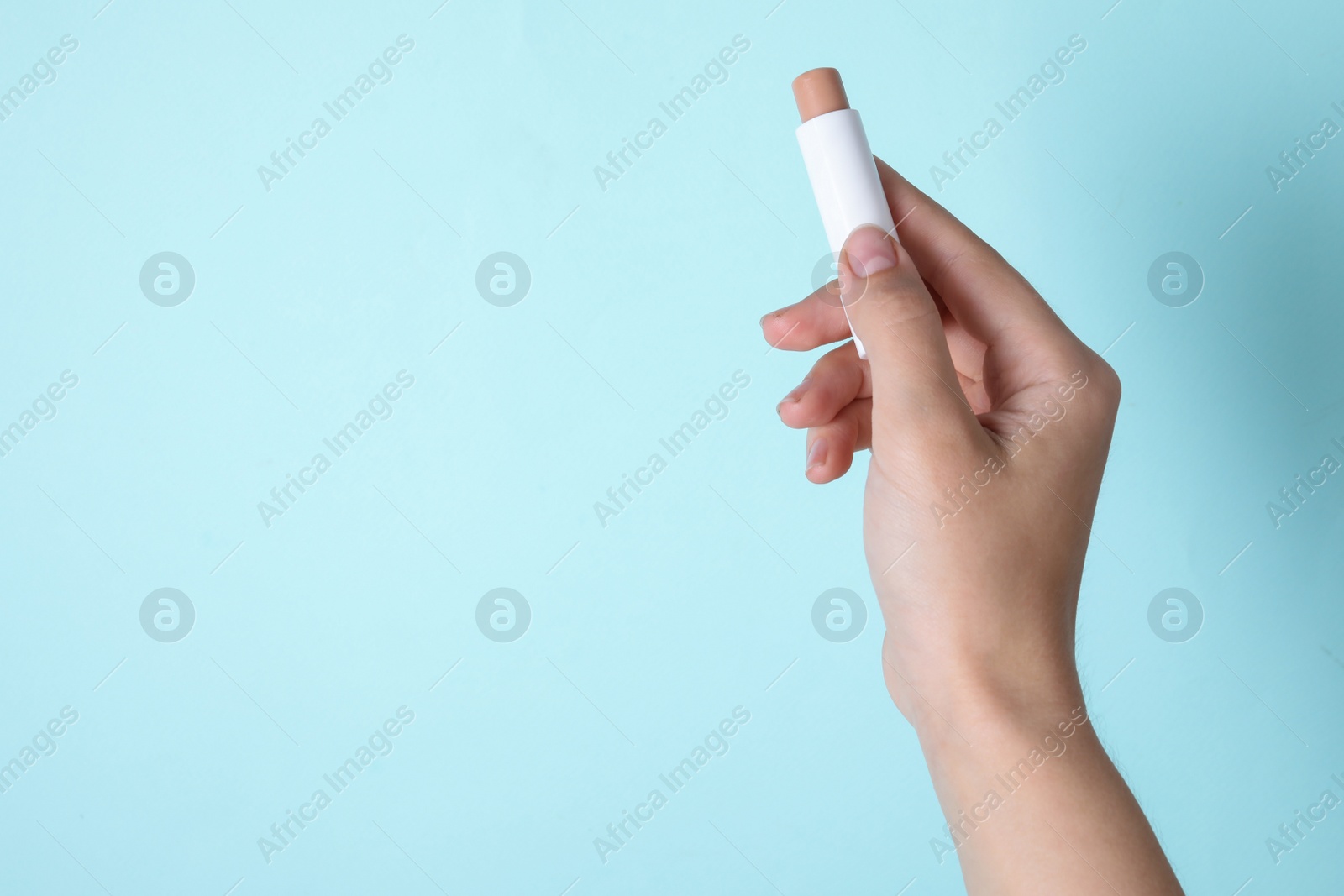 Photo of Woman holding hygienic lipstick on turquoise background, closeup. Space for text