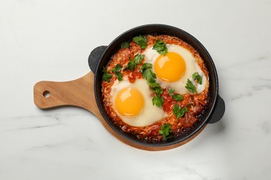 Photo of Delicious shakshuka in frying pan on white marble table, top view
