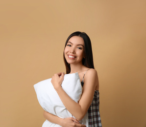 Photo of Beautiful Asian woman with pillow on beige background. Bedtime