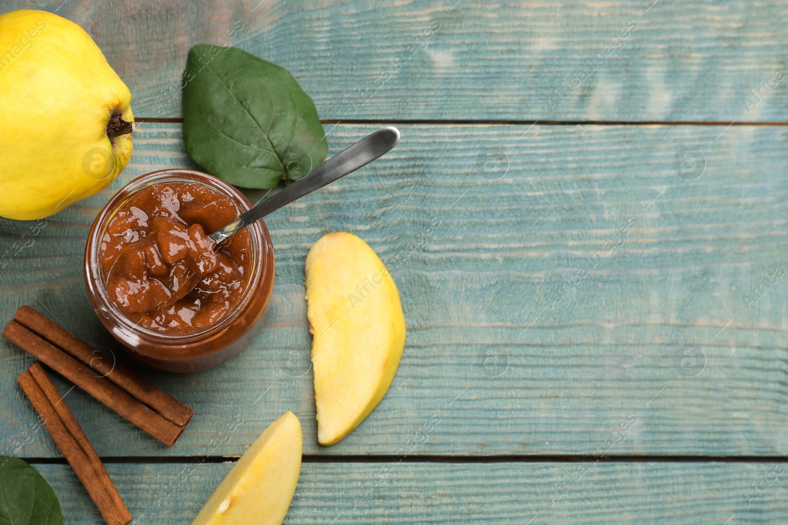 Photo of Delicious quince jam, fruits and cinnamon on blue wooden table, flat lay. Space for text