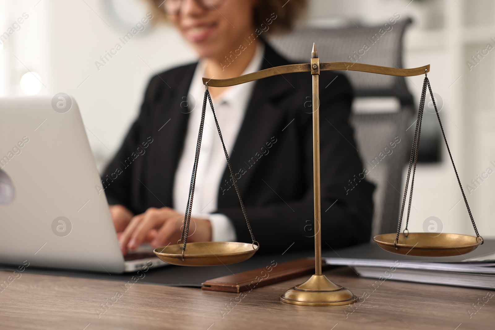 Photo of Notary using laptop at workplace in office, focus on scales of justice