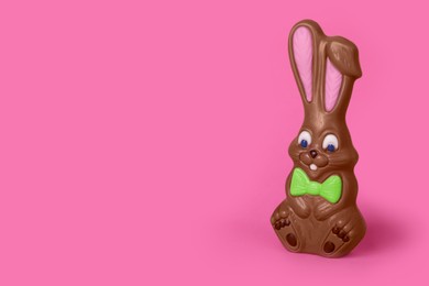 Photo of Chocolate bunny on pink background, space for text. Easter celebration