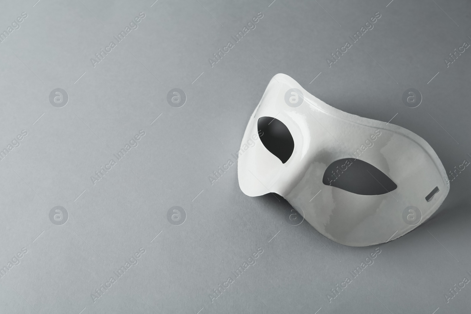 Photo of White theatre mask on grey background, space for text
