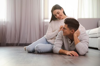 Photo of Happy couple on warm floor at home, space for text. Heating system