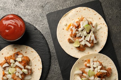 Photo of Delicious tacos with vegetables, meat and ketchup on grey textured table, flat lay