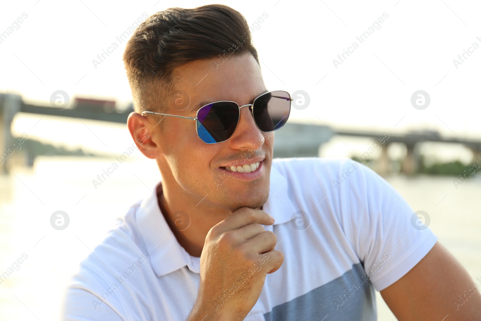 Photo of Handsome man wearing stylish sunglasses near river