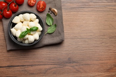 Photo of Delicious mozzarella balls, tomatoes and garlic on wooden table, flat lay. Space for text
