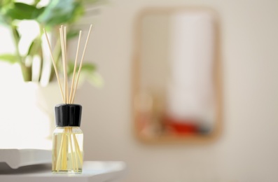 Aromatic reed air freshener on table against blurred background