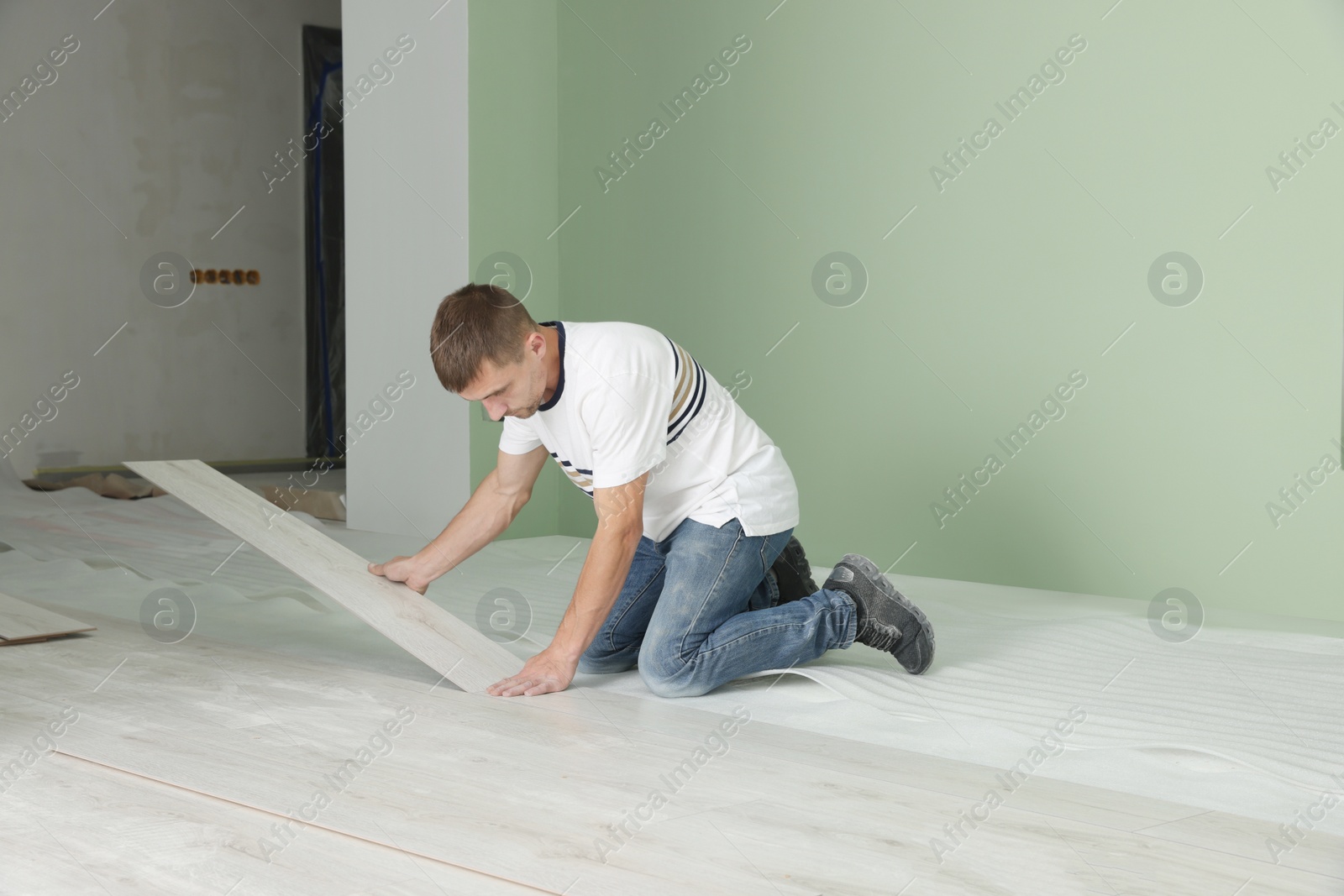 Photo of Man installing new laminate flooring in room