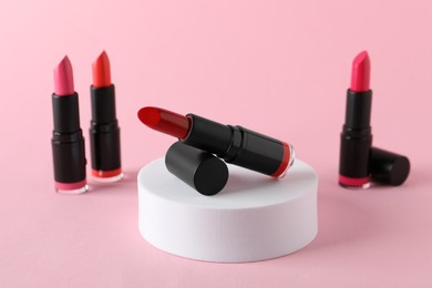Different beautiful glossy lipsticks on pink background