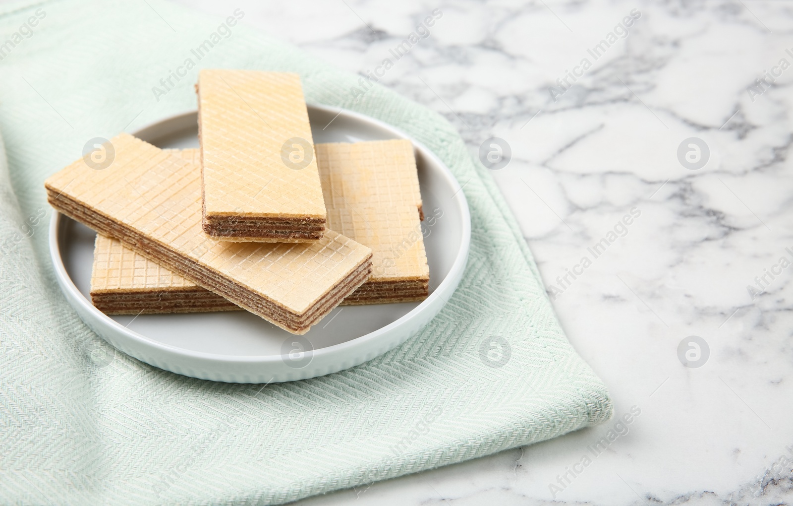 Photo of Plate of delicious wafers on marble background. Space for text