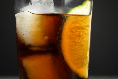 Photo of Glass of refreshing soda drink with lime and ice cubes on grey background, closeup