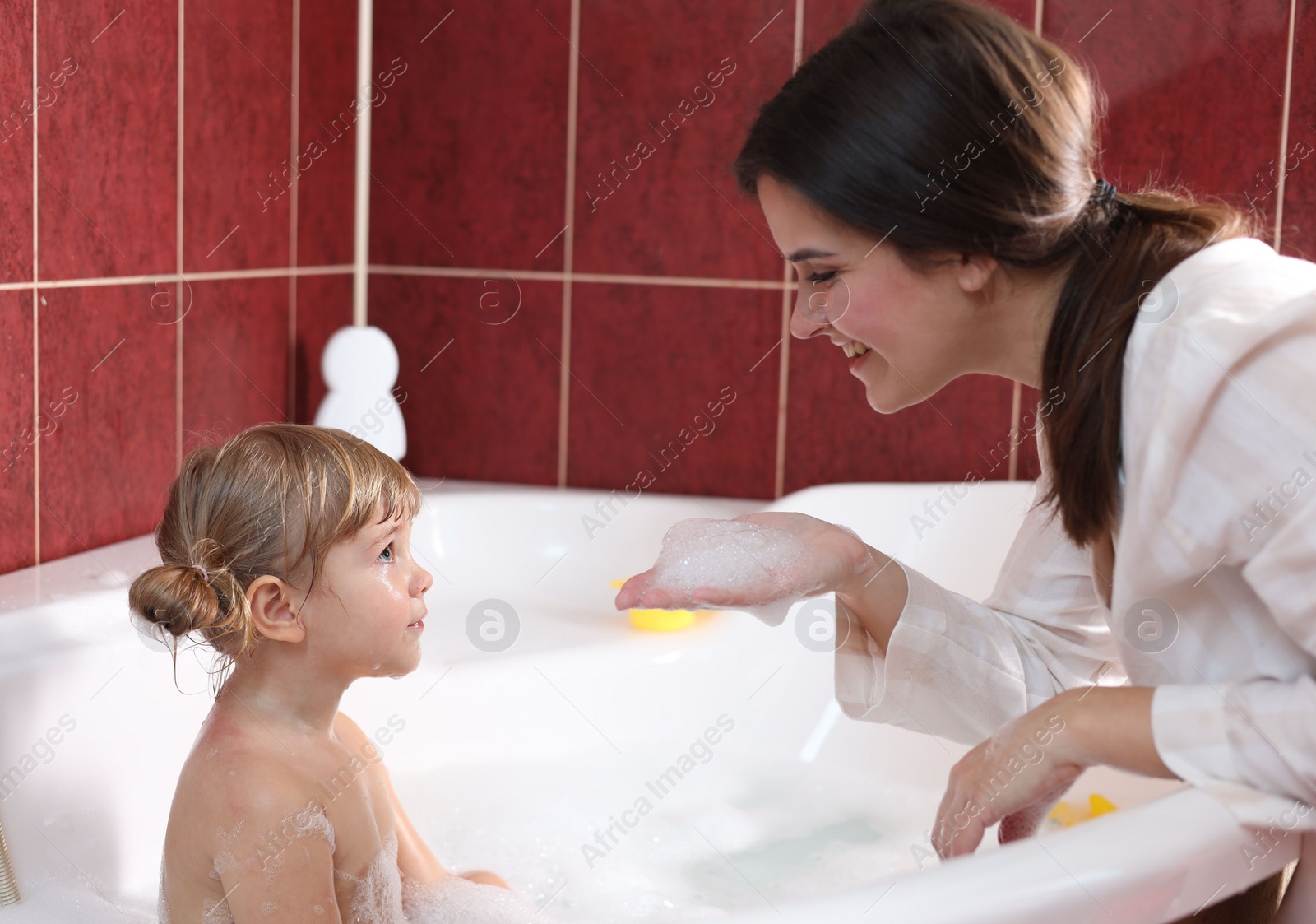 Photo of Happy mother with her little daughter spending time together in bathroom