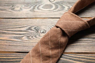 Photo of One striped necktie on wooden table, above view. Space for text