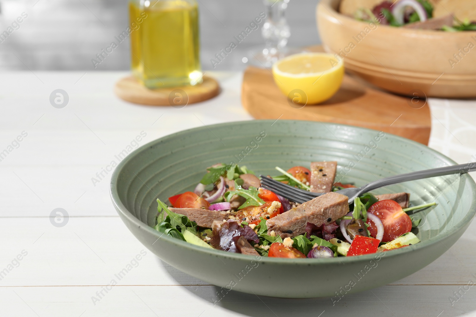 Photo of Delicious salad with beef tongue, vegetables and fork served on white wooden table