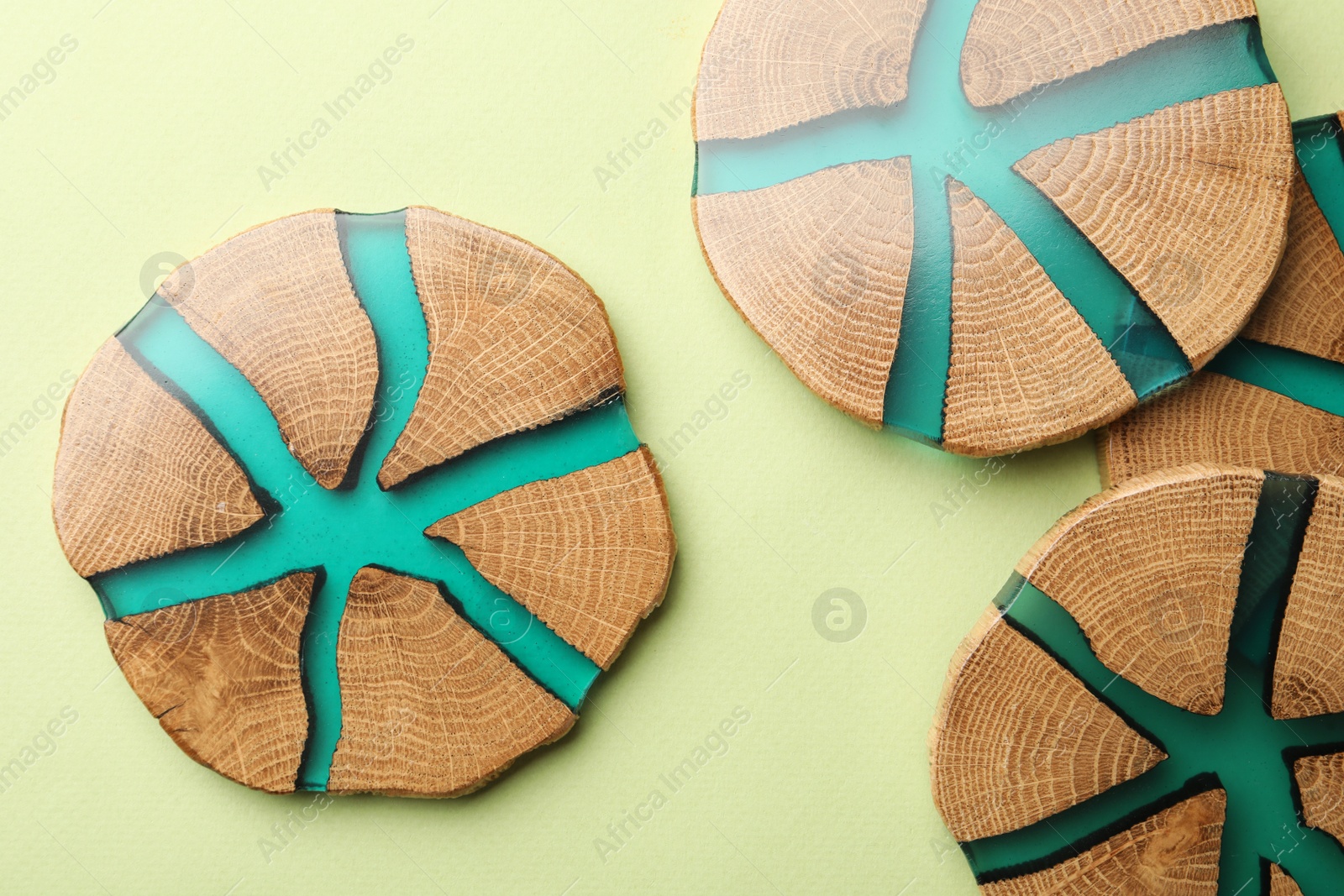 Photo of Stylish wooden cup coasters on pale green background, flat lay