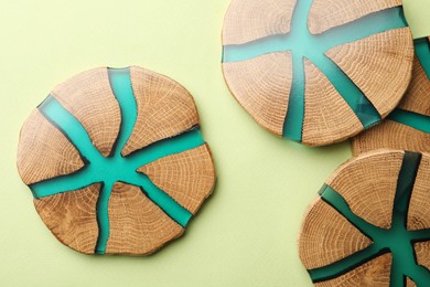 Stylish wooden cup coasters on pale green background, flat lay