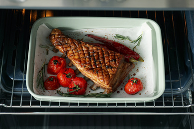 Photo of Delicious roasted ribs with tomatoes in oven