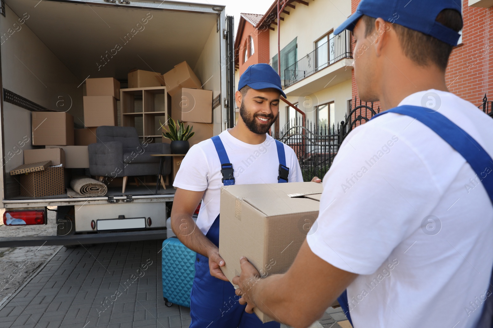 Photo of Workers unloading boxes from van outdoors. Moving service