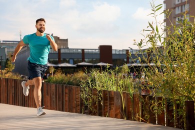 Photo of Smiling man running outdoors on sunny day. Space for text