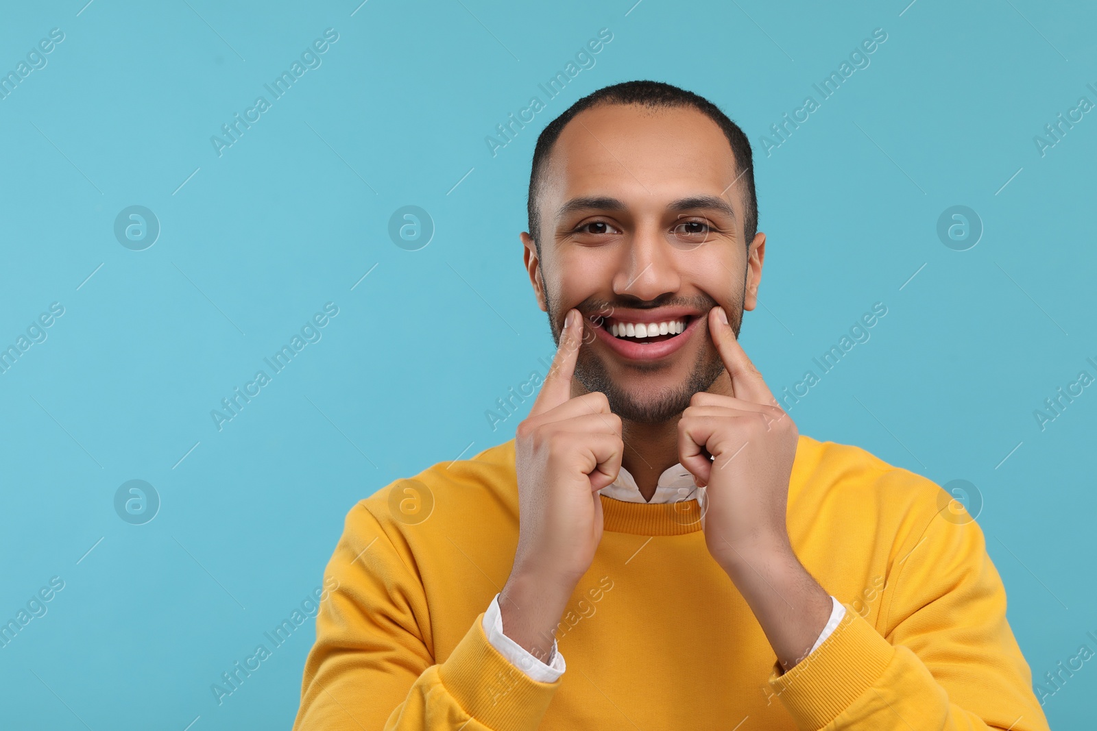 Photo of Smiling man with healthy clean teeth on light blue background. Space for text