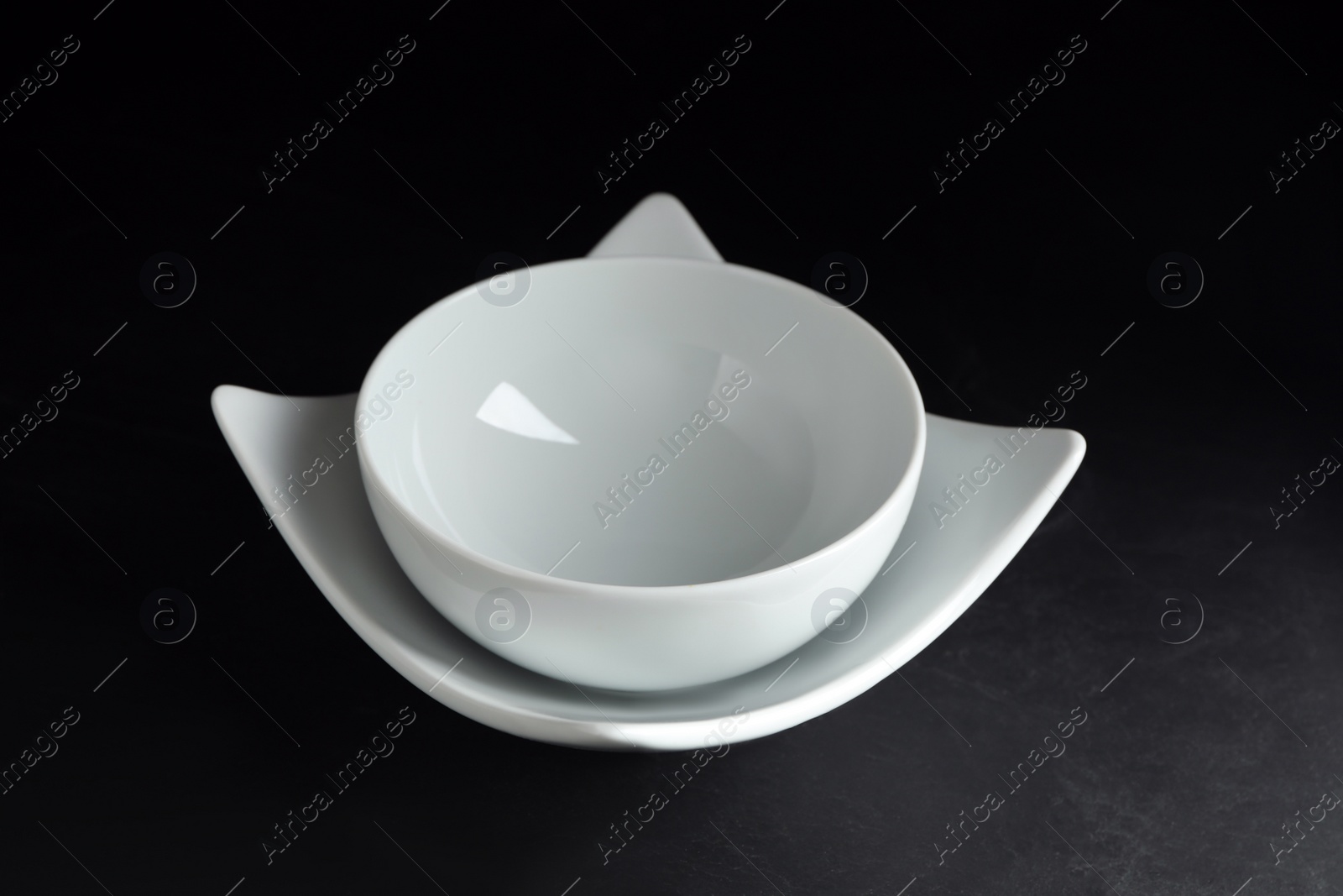 Photo of Empty ceramic plate and bowl on black stone table, closeup