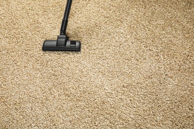 Photo of Removing dirt from beige carpet with modern vacuum cleaner. Space for text