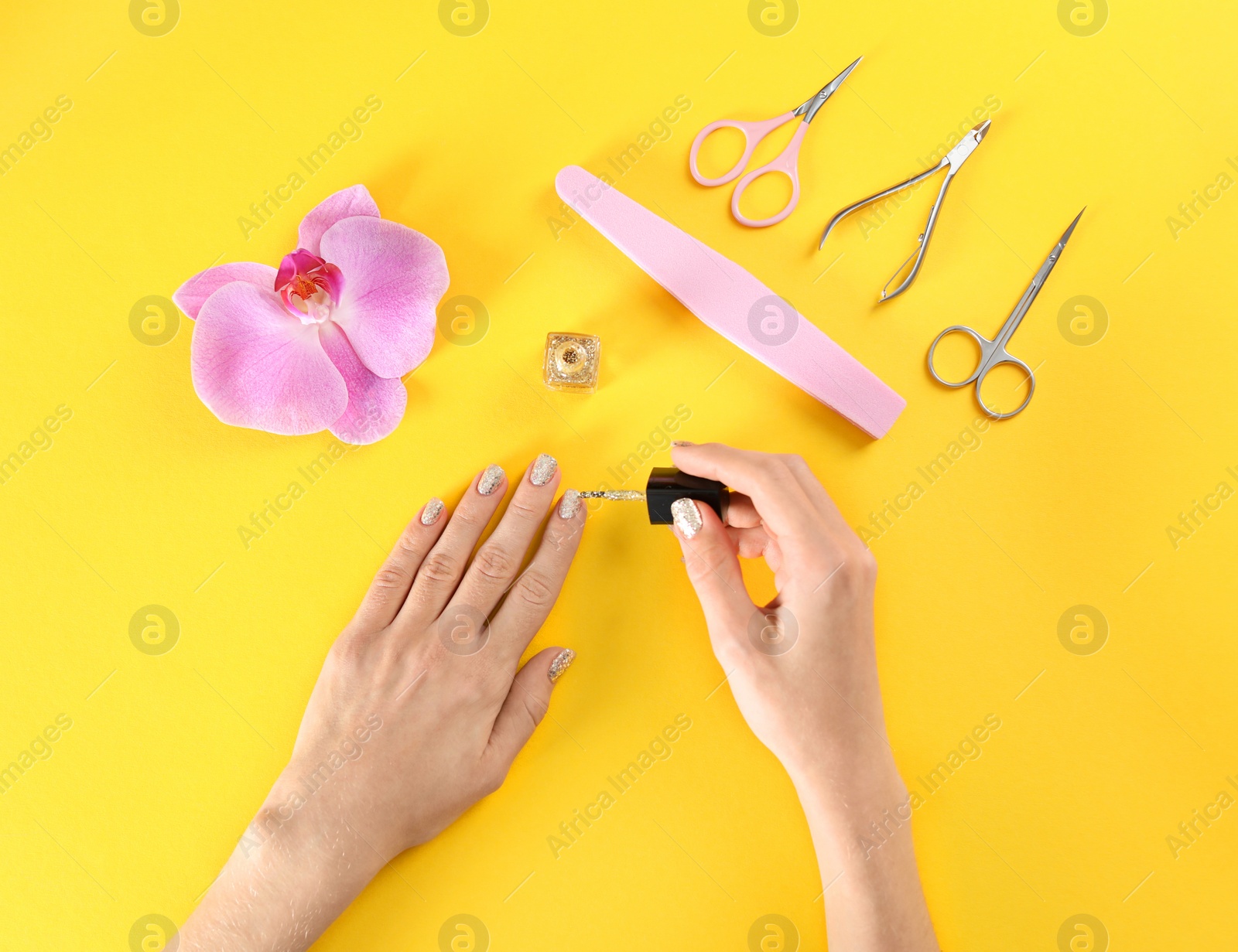 Photo of Woman applying nail polish on color background, top view