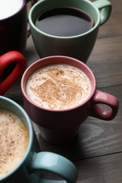 Many different cups with aromatic hot coffee on wooden table