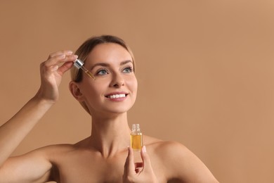 Photo of Beautiful woman applying cosmetic serum onto her face on beige background, space for text
