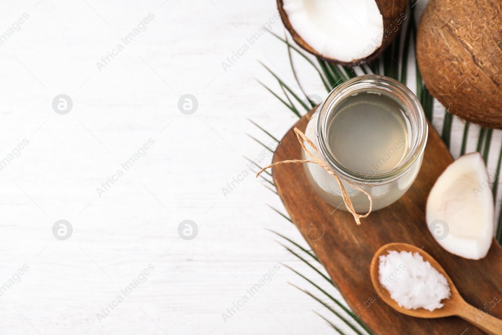 Photo of Coconut oil on white wooden table, flat lay. Space for text