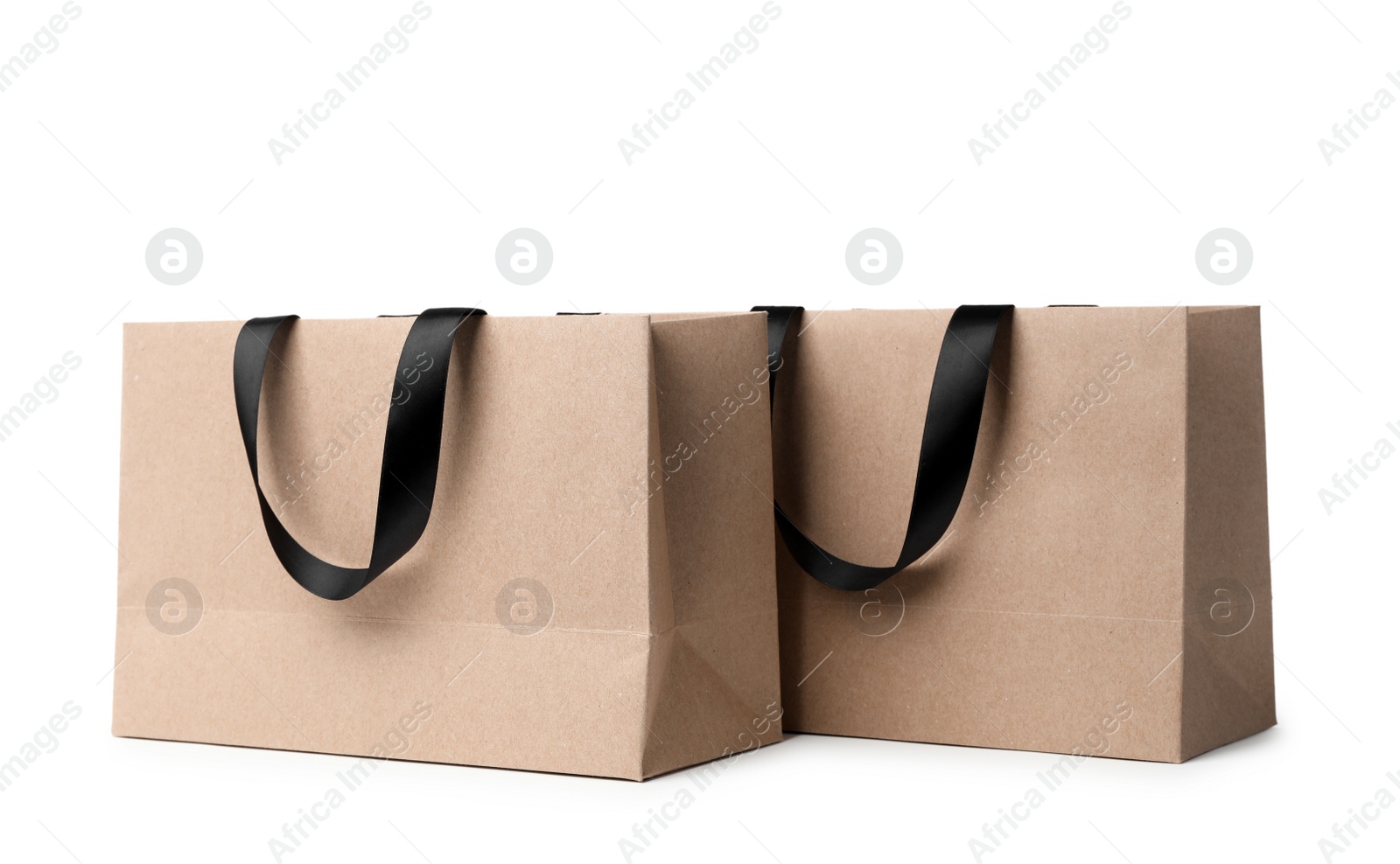 Photo of Paper shopping bags with ribbon handles on white background. Mockup for design