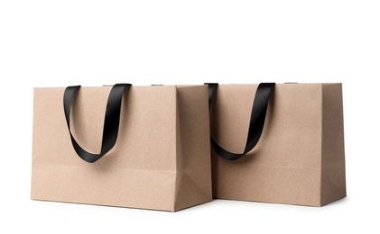 Paper shopping bags with ribbon handles on white background. Mockup for design