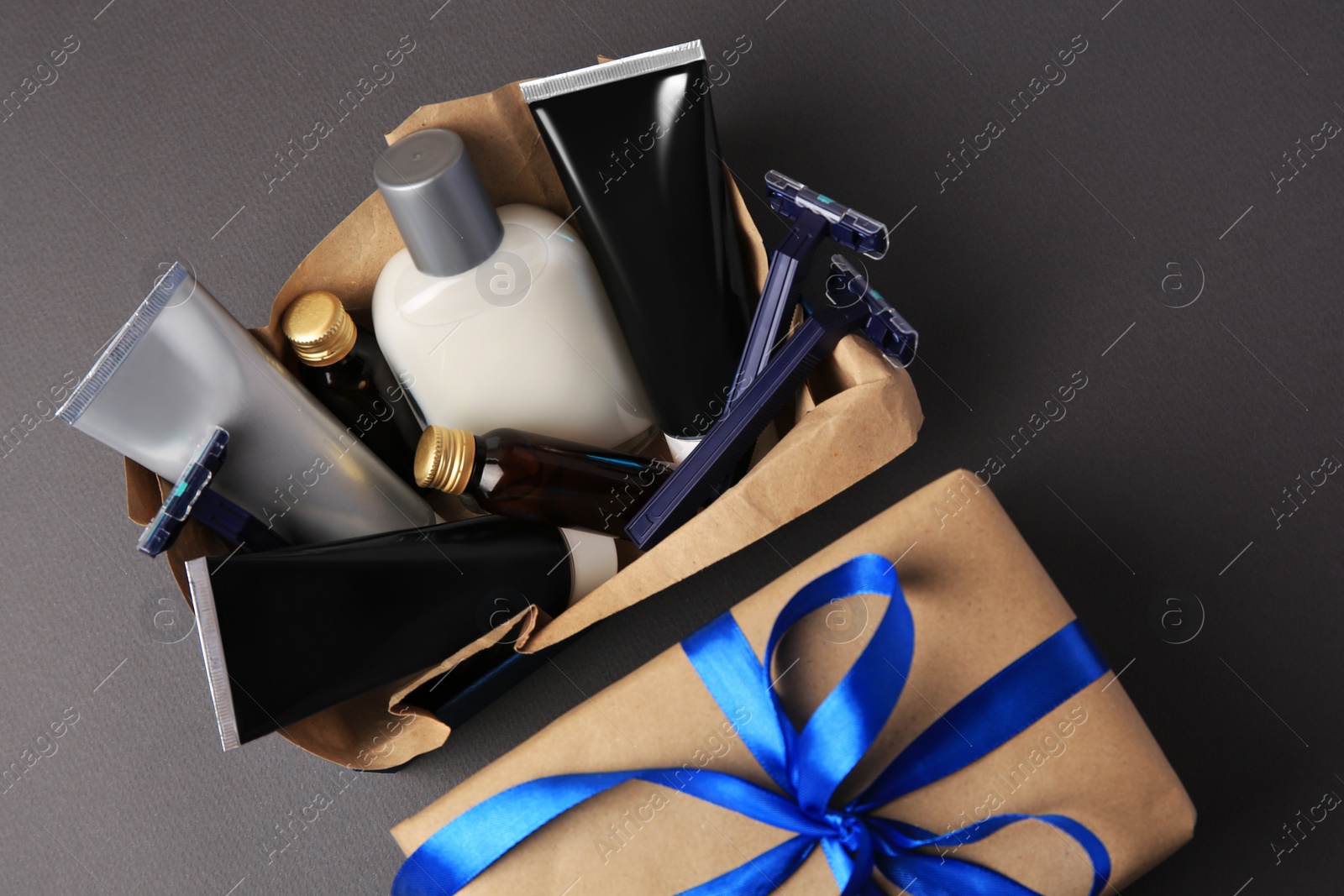 Photo of Gift box with different men's shaving accessories and cosmetics on dark grey background, flat lay