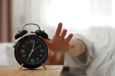 Photo of Woman turning off alarm clock in bedroom, focus on hand. Space for text