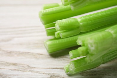 Fresh green celery on white wooden table, closeup. Space for text