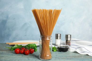 Uncooked buckwheat noodles and fresh ingredients on blue wooden table