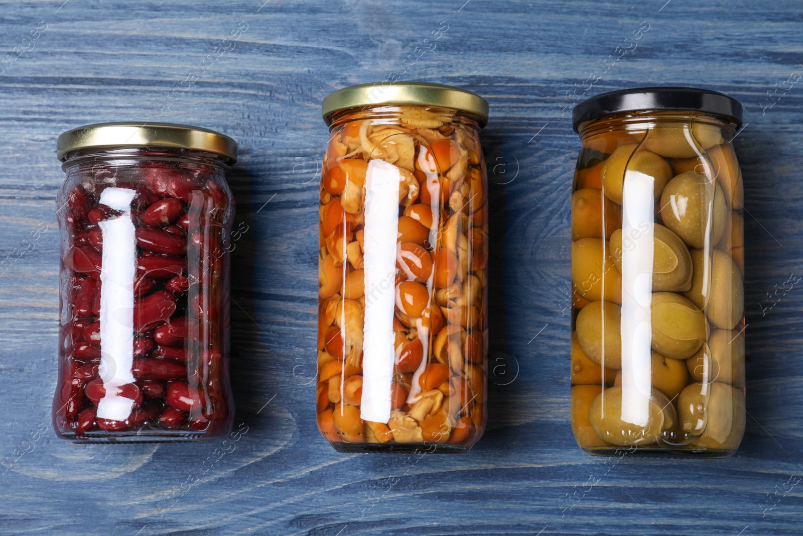 Photo of Glass jars with different pickled vegetables on blue wooden table, flat lay